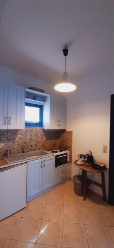 a kitchen with white cabinets and a table in it at Thalassa house by the sea in Áyios Yeóryios