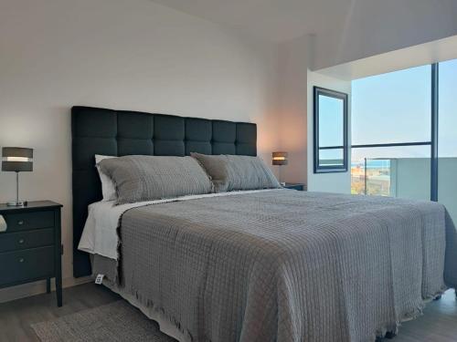 a bedroom with a large bed with a large window at Encantador depto 2D2B con estacionamiento vista al MAR ServicioHOM in Antofagasta