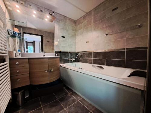 een badkamer met een bad, een wastafel en een spiegel bij Aldébaran - maeva Home - Appartement pièces - Prestige 924 in Arâches-la-Frasse