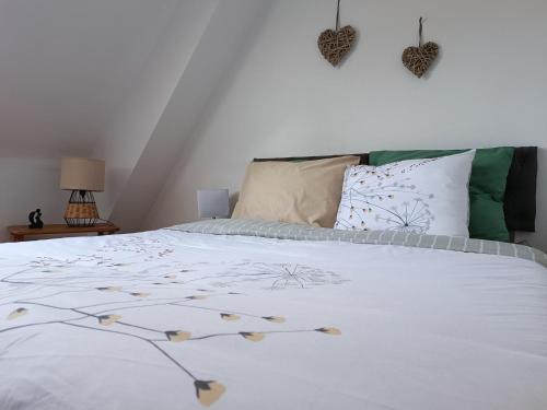 una camera da letto con letto, lenzuola e cuscini bianchi di Vue unique sur le Mont St Michel a Huisnes-sur-Mer