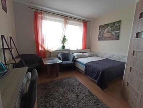 a bedroom with a bed and a couch and a window at Pokoje AGA in Mikołajki