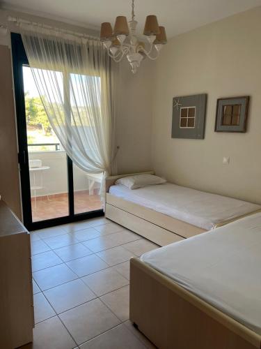 a bedroom with two beds and a large window at Skioni Soula Apartment in Nea Skioni