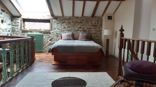 a bedroom with a bed and a stone wall at Au coeur des loges in Saint-Bonnet-de-Bellac