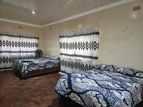 a bedroom with two beds and two curtains at Stay Sunrise in Nelspruit