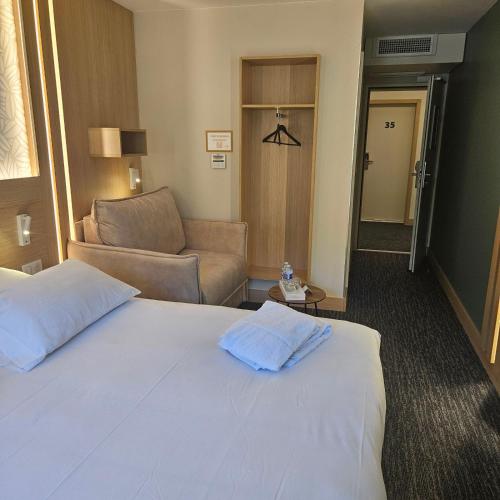 a hotel room with a bed and a couch at Hôtel Aster Restaurant Aux Arcades in Briey