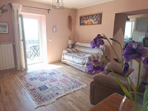 uma sala de estar com um sofá e uma mesa com flores roxas em Casa Bellavista em Montefegatesi