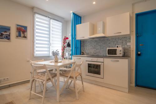 une cuisine avec une table et des chaises et un micro-ondes dans l'établissement Évasion Santorin - Jacuzzi & Relax, au Havre