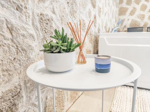 una mesa blanca con una planta y una taza en ella en Évasion Santorin - Jacuzzi & Relax, en Le Havre