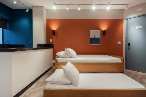 2 camas en una habitación con paredes de color naranja en BHomy Jardins - Aconchegante no melhor local HP26, en São Paulo