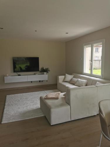 sala de estar con sofá blanco y TV en Chambres d'hôtes chez Manon, en Sampans