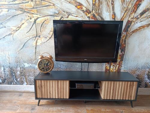 a tv on top of a stand with a clock at Sweet Heart Home in Szczecin