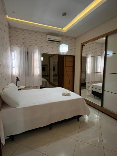 ein Schlafzimmer mit einem großen weißen Bett und einem Spiegel in der Unterkunft Casa Confort in Juazeiro do Norte