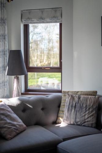 a couch in a living room with a window at Glen Lodge in Ballymoney