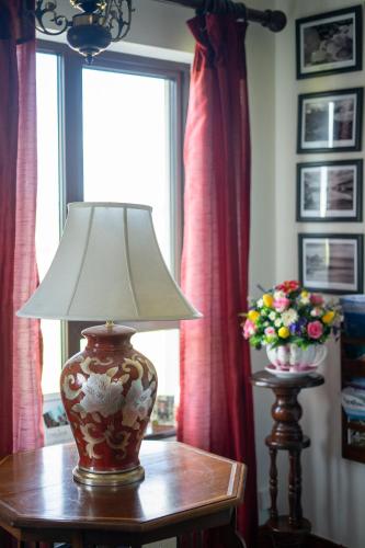 a lamp on a table with a vase of flowers at Glen Lodge in Ballymoney