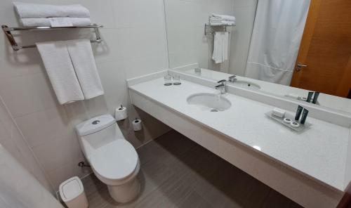 a white bathroom with a toilet and a sink at Hotel Diego de Almagro Pudahuel Aeropuerto in Santiago