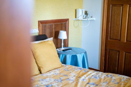 a bedroom with a bed and a table with a lamp at Glen Lodge in Ballymoney