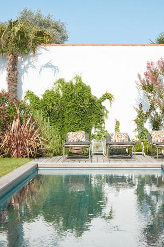 deux chaises et une table à côté d'une piscine dans l'établissement Maisons 322 - Maison La Flamboyante, au Bois-Plage-en-Ré