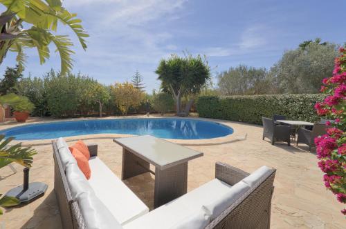a swimming pool with a white couch and a table at Can Juanito in Playa d'en Bossa