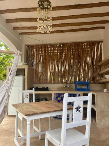 a kitchen with a table and two white chairs at Mgongo tree house in Jambiani