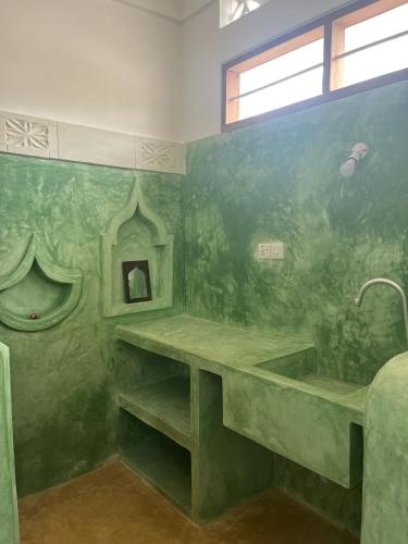 a green bathroom with a tub and a sink at Mgongo tree house in Jambiani