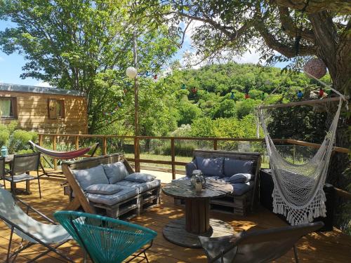 un patio con sillas, una mesa y una hamaca en Roulotte la clé du Luberon, en Buoux