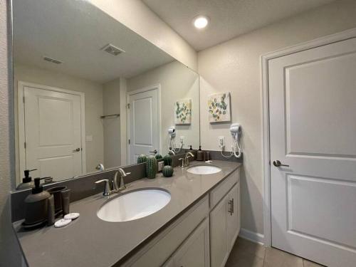 a bathroom with two sinks and a large mirror at 4BR Townhouse Private Pool BBQ Near Disney in Kissimmee