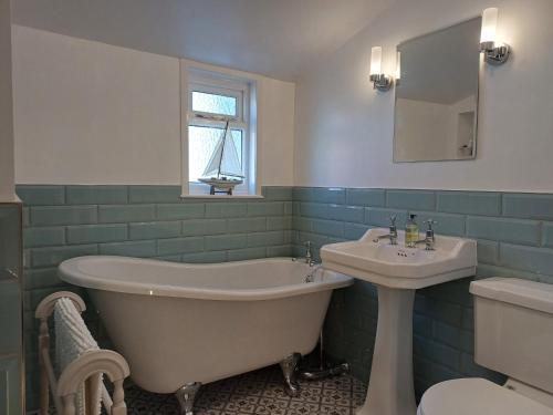 a bathroom with a bath tub and a sink at Creel Cottage in Cullen