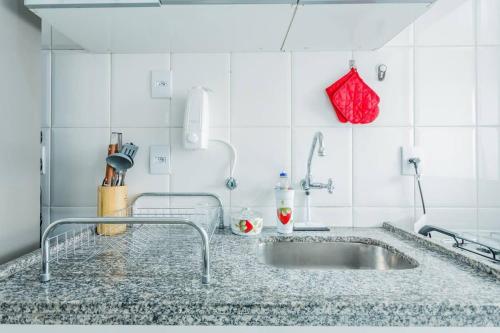 - un comptoir de cuisine avec un évier et un porte-monnaie rouge dans l'établissement BHomy Pompéia Muito bem localizado FI33, à São Paulo