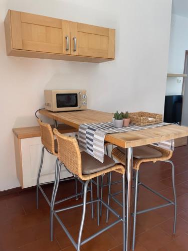 eine Küche mit einem Tisch mit Stühlen und einer Mikrowelle in der Unterkunft Appartamento Gaia - a due passi dal centro in Laveno-Mombello