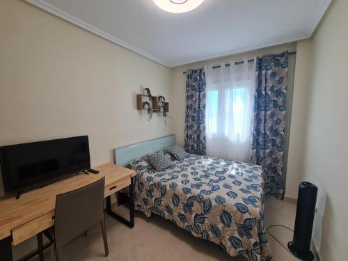 a bedroom with a bed and a desk with a television at Ap-to Frente al Mar VillaRomana in Roquetas de Mar