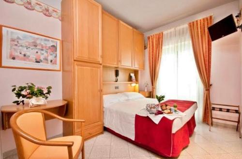 a bedroom with a bed with a table and a chair at Hotel Kennedy in Rimini