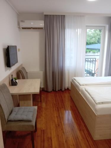a bedroom with a bed and a table and a window at Apartment Atina in Subotica
