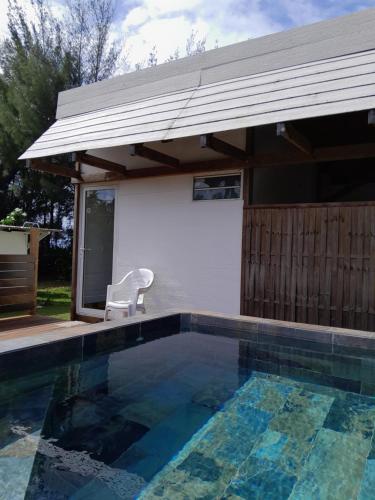 una piscina con una silla junto a una casa en Mara'ai le spot Tubuai Chambre triple Taahueia Deluxe SDB privée avec piscine, en Tubuai