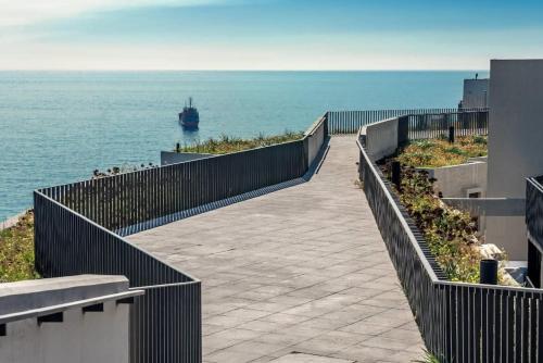 a walkway leading to the ocean with a ship in the distance at HOM I En Cerro Baron Cómodo Loft Jardín, Estacionamiento 1709 in Valparaíso