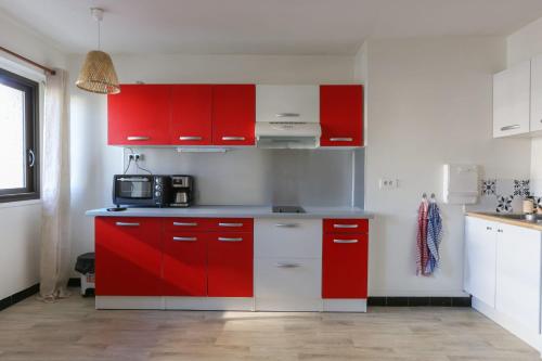 a red kitchen with white and red cabinets at 32 m love nest studio with balcony in Paris