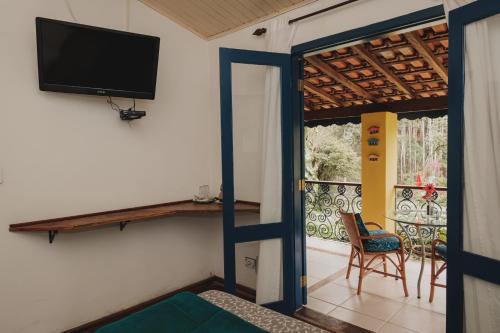um quarto com uma televisão e uma varanda com uma cadeira em A Casa da Fazenda em Santo Antônio do Pinhal