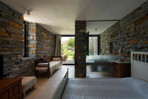a bedroom with a stone wall with a bed and a tub at House garden in Ioulis