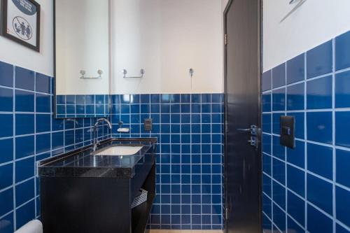 a bathroom with blue tiled walls and a sink at BHomy Paulista Na Av Paulista com design BA608 in São Paulo