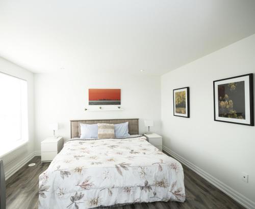 een witte slaapkamer met een bed en 2 ramen bij Executive 3 Bedroom Town House in Mississauga
