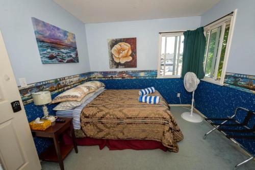 亞博斯福的住宿－Anita's Bed & Breakfast In Abbotsford - Choose your Room Upstairs - S-1 - S-2 - S-3，一间卧室配有一张床、一张桌子和风扇