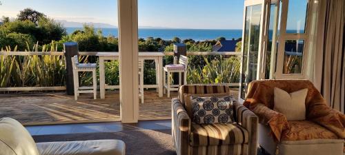 a living room with chairs and a view of the ocean at Coastal Chic in Pohara in Pohara