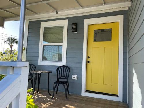 a yellow door on a gray house with a table and chairs at Updated,spacious, maritime 3BR downtown cottage in St. Augustine