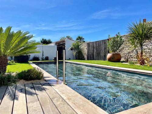 a swimming pool in a yard with a wooden deck at Maisons 322 - La Flamboyante in Le Bois-Plage-en-Ré
