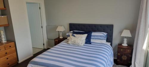 a bedroom with a bed with blue and white striped sheets at Coastal Chic in Pohara in Pohara