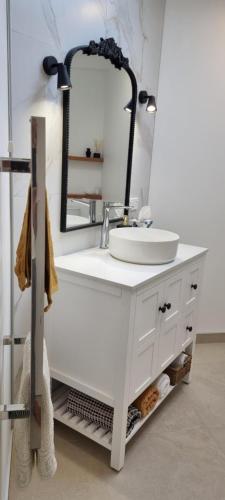 a bathroom vanity with a sink and a mirror at Coastal Chic in Pohara in Pohara