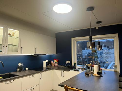 cocina con armarios blancos y ventana grande en Arendalsuka - Fin enebolig, sentralt og sjønært,gratis parkering 4 rom 3 bad 2 stuer en Arendal