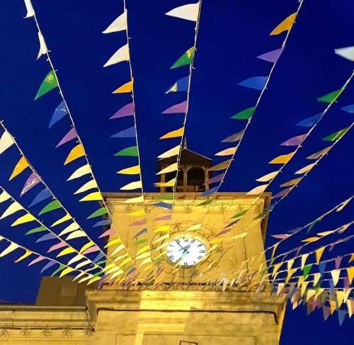 a clock tower with colorful flags on top of it at La Buguoise in Le Bugue