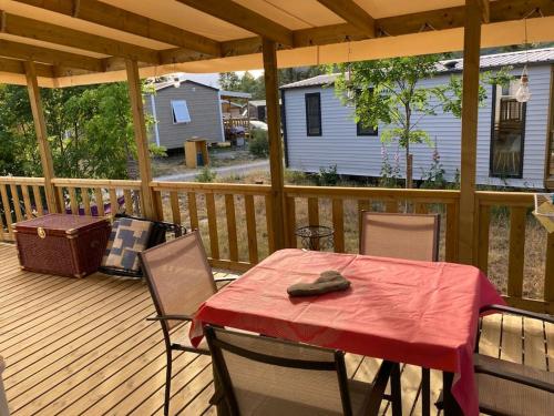 une terrasse en bois avec une table et des chaises dessus dans l'établissement mobilhome entre montagne et lac près de Gap au calme, à Rochebrune