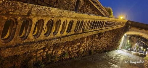 a stone wall with a bridge in a city at night at La Buguoise in Le Bugue