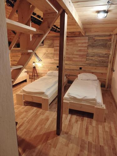 two beds in a room with wooden walls at Osada Brzeziny - 25 minut od Warszawy - sauna, balia z jacuzzi, basen, altana, grill, ogród, ognisko in Brzeziny